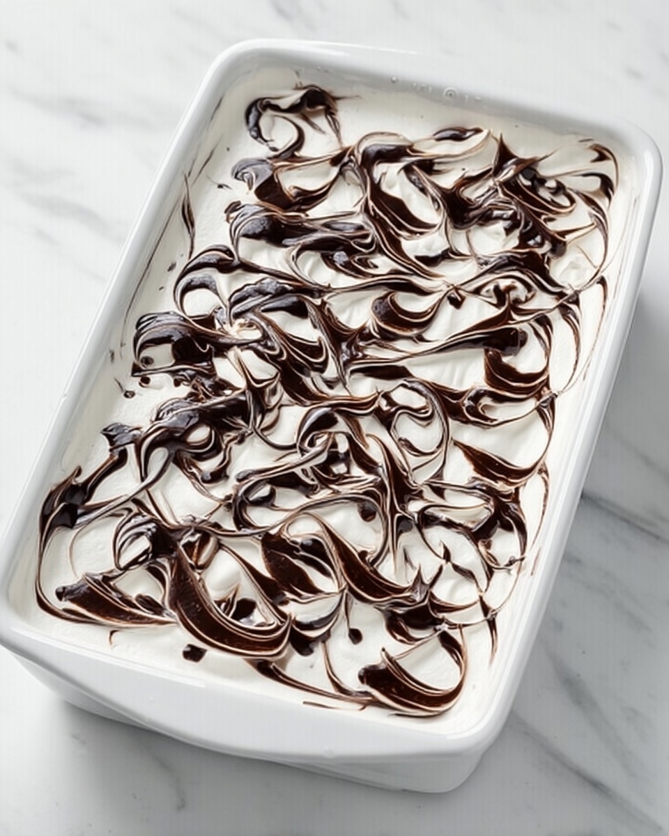 A white rectangular dish is filled with a smooth, white creamy layer that covers the entire surface evenly. On top, dark chocolate sauce is spread in random swirling patterns, creating a striking contrast against the white cream. The chocolate forms thin, wavy lines and curves across the top, giving a marbled effect. The dish sits on a white marbled surface. photo taken with an iphone --ar 4:5 --v 7