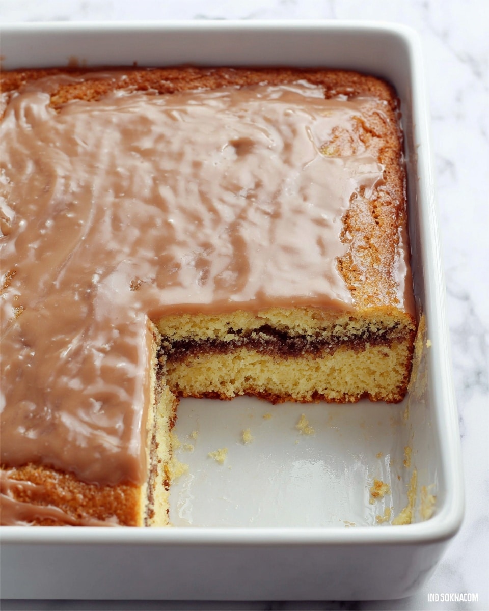 A white rectangular baking dish holds a square cake with two visible layers; the bottom layer is pale yellow with a soft texture, the middle layer is a darker brown filling that looks moist and slightly crumbly, and the cake is topped with a smooth, light brown glaze that spreads evenly across the surface, with a small corner piece removed to reveal the layers inside. The background features a white marbled texture. photo taken with an iphone --ar 4:5 --v 7