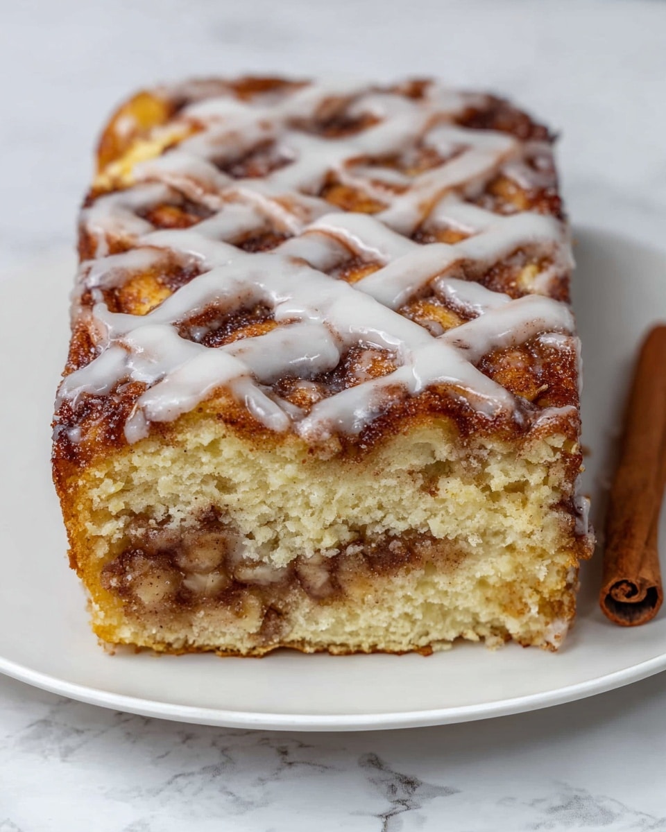 A rectangular cinnamon roll cake with visible layers sits on a white plate with a white marbled surface background. The top layer is golden brown with a lattice pattern of baked cinnamon strips, covered by a glossy white icing spread unevenly over the top and sides. Below the top layer, you can see a soft and fluffy light yellow cake layer, with a cinnamon filling in the middle and at the bottom, showing a rich brown color with small chunks. A cinnamon stick is placed near the cake on the plate. The photo is taken with an iphone --ar 4:5 --v 7