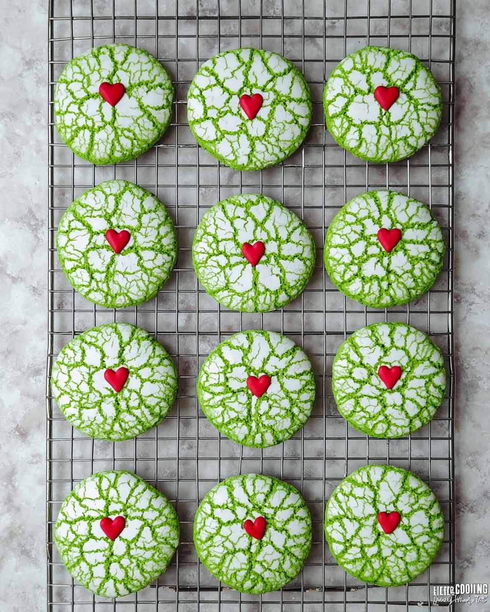 Twelve round cookies with a bright green base and white cracked icing on top are arranged neatly on a cooling rack. Each cookie has a small red heart in the center. The surface below is a white marbled texture. The texture of the cookies looks soft with a slightly rough cracked pattern on the icing. photo taken with an iphone --ar 4:5 --v 7