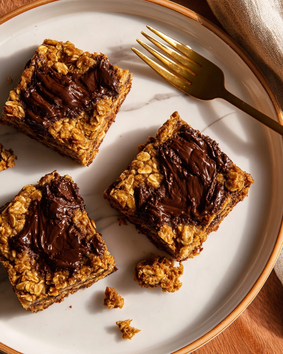 Three square oatmeal bars with a rough texture sit spaced on a white plate with a thin gold rim. Each bar is golden brown with visible oats and has smooth, dark chocolate patches melted unevenly on top and inside. There are small crumbs scattered on the plate around the bars. In the upper right corner, a gold fork rests on a white marbled surface next to the plate. The lighting is warm and soft, highlighting the textures. Photo taken with an iphone --ar 4:5 --v 7