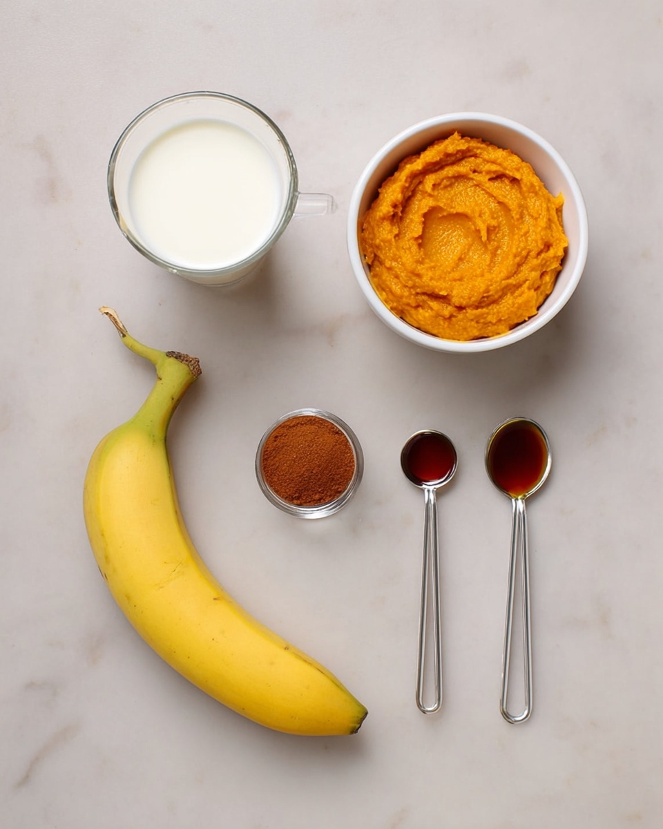 The image shows five ingredients arranged on a white marbled surface: a white bowl filled with bright orange pumpkin puree at the top right; a clear glass cup filled with white milk at the top left; a yellow banana with a green stem at the bottom left; a small silver measuring spoon with brown cinnamon powder to the right of the banana; and a slightly larger silver measuring spoon filled with dark amber maple syrup next to the cinnamon spoon on the right. The items are spaced out neatly and viewed from above. photo taken with an iphone --ar 4:5 --v 7