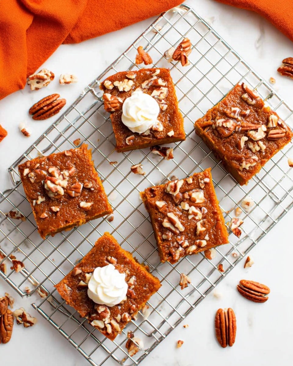 There are six square pumpkin bars with nuts on top placed on a silver wire cooling rack over a white marbled surface. Each bar has a dense orange-brown layer with a slightly rough texture and is sprinkled with chopped pecans and cinnamon sugar pieces in uneven clusters. Two bars have small swirls of white cream on top, one in the center and the other near the edge. Around the rack, whole and halved pecans are scattered on the white marbled surface. An orange cloth is partly visible on the top left corner. Photo taken with an iphone --ar 4:5 --v 7