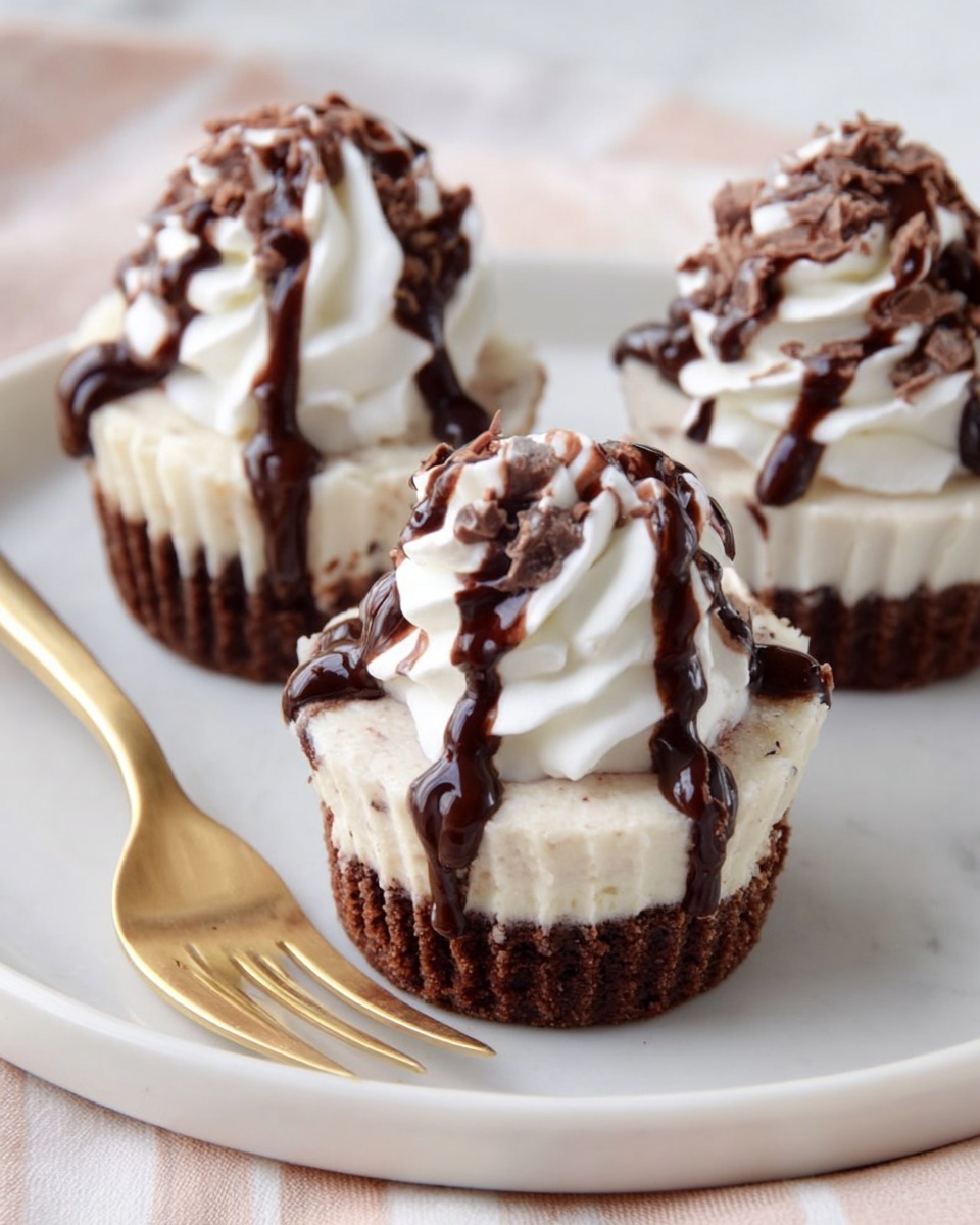 Three small dessert cupcakes sit on a white plate over a white marbled surface. Each cupcake has two layers: a dark brown, crumbly looking bottom layer and a light cream-colored, smooth middle layer. On top of each cupcake is a swirl of soft white whipped cream, drizzled with thick dark chocolate sauce that runs down the sides slightly. A gold and white fork lies on the plate next to the front cupcake. Photo taken with an iphone --ar 4:5 --v 7