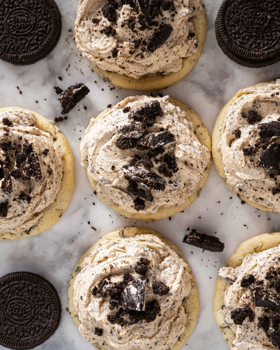 The image shows several light beige cookies with a soft, slightly cracked texture, each topped with a thick layer of creamy light brown frosting mixed with small dark cookie crumbs. On top of the frosting, there are chunks and pieces of dark chocolate sandwich cookies scattered unevenly. Around the cookies, whole dark chocolate sandwich cookies are placed on a white marbled surface. The cookies are arranged close to each other in a loose group. photo taken with an iphone --ar 4:5 --v 7