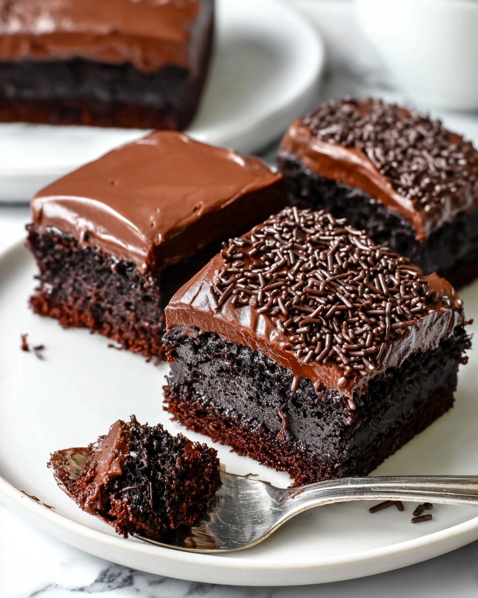 The image shows three pieces of rich chocolate cake on a white plate placed on a white marbled surface. Each cake piece has two layers: a dark, moist chocolate base and a thick, smooth chocolate frosting layer on top. The piece in the front is covered with fine chocolate sprinkles, and a spoon holds a bite-sized piece of cake with visible chocolate sprinkles and creamy frosting. The other two cake pieces in the background have plain shiny frosting. photo taken with an iphone --ar 4:5 --v 7