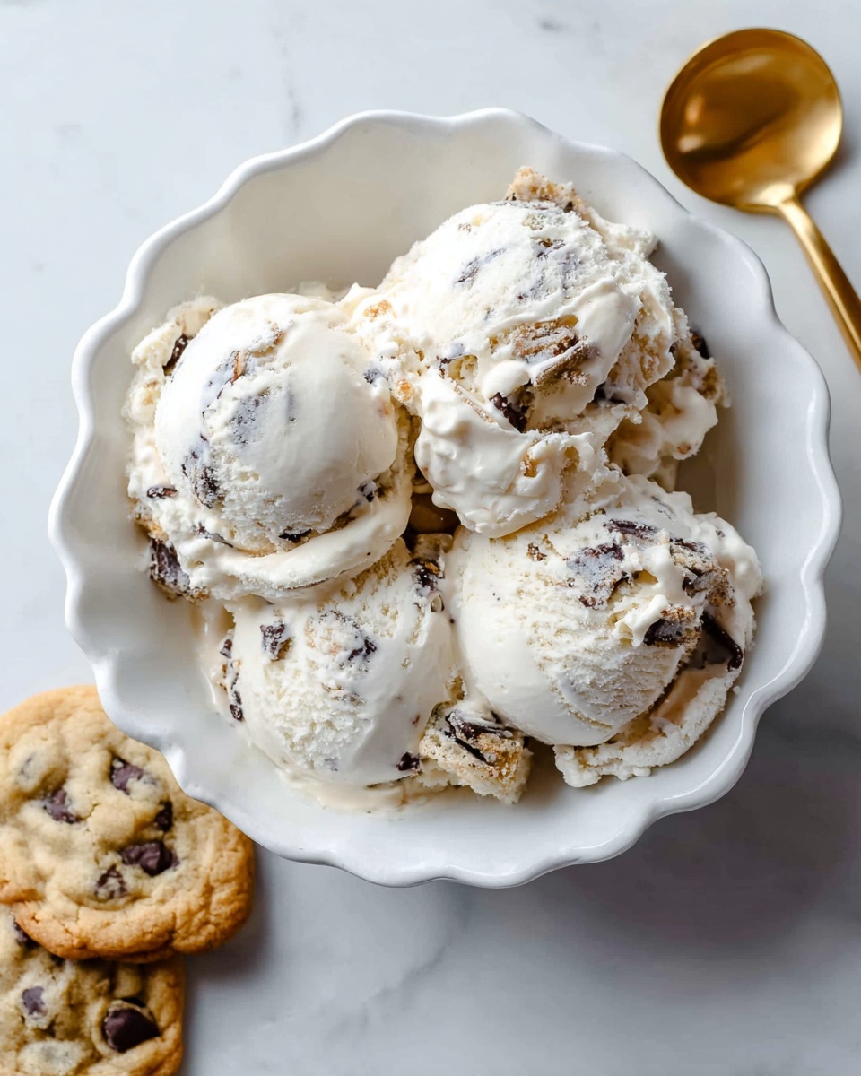 A white scalloped bowl filled with four scoops of creamy white ice cream that has visible chunks of chocolate and cookie pieces mixed inside. The ice cream looks soft and slightly melting. The bowl is placed on a smooth white marbled surface with a gold spoon resting beside the ice cream inside the bowl. Two chocolate chip cookies are lying on the marble surface near the bowl, showing a golden-baked texture with dark chocolate chips. The scene is bright and clean. photo taken with an iphone --ar 4:5 --v 7