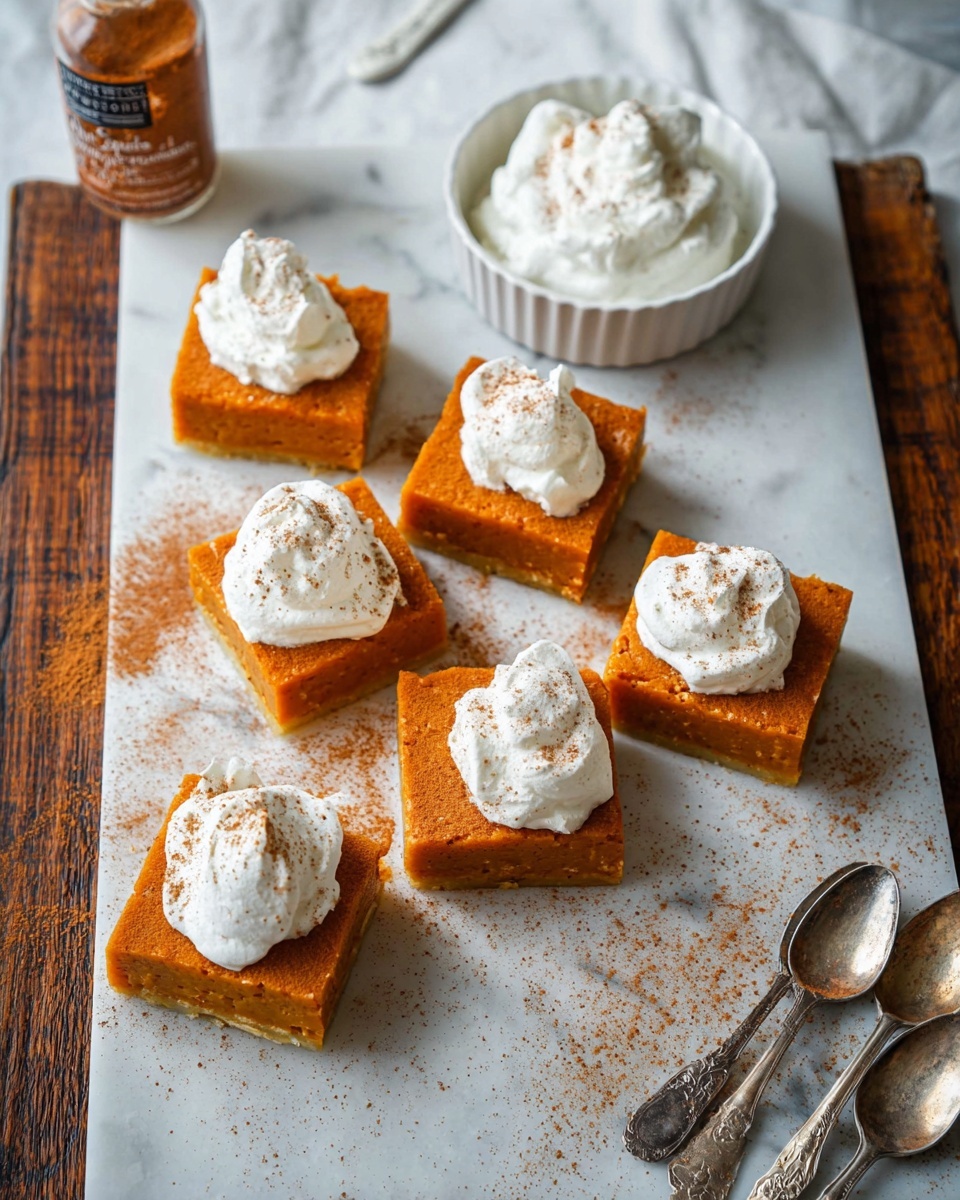 The image shows six square pieces of orange dessert with a smooth texture, arranged on white marbled paper over a dark wooden surface. Each piece has a dollop of white whipped cream on top, sprinkled lightly with brown powder. Near the top center of the image, there is a small white bowl piled high with more whipped cream. To the right of the bowl, two antique silver spoons rest on the white marbled surface. On the left side, a bottle labeled pumpkin spice seasoning lies on its side with some spilled powder next to it. The scene is bright and clear, with a cozy and inviting feeling. Photo taken with an iphone --ar 4:5 --v 7