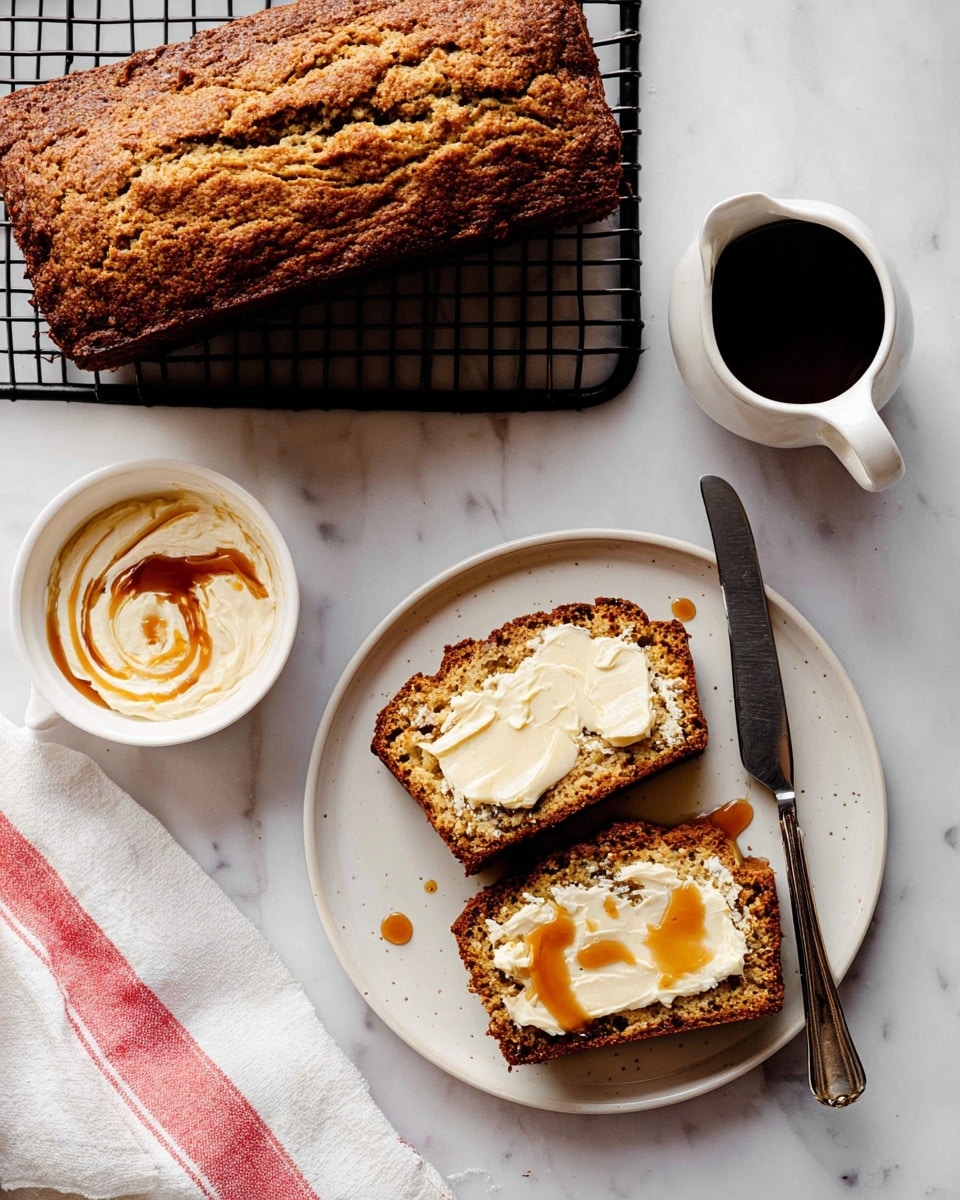 A loaf of golden brown bread with a rough textured crust sits on a black cooling rack in the upper left corner on a white marbled surface. Below it, two slices of the bread are placed on a white plate, each slice topped with a thick layer of creamy white spread and drizzled with light brown syrup that pools slightly on the plate. A silver knife rests on the plate beside the bread slices. To the left, a small white bowl holds more of the creamy spread with syrup swirled on top. In the upper right corner, a white small pitcher filled with dark syrup adds contrast. A white cloth with red stripes is folded nearby. Photo taken with an iphone --ar 4:5 --v 7