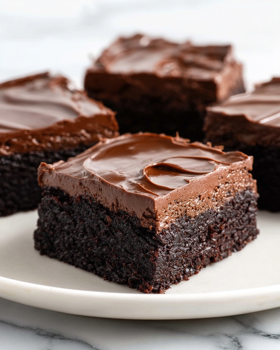 The image shows three square chocolate brownies on a white plate, each with two layers: a dark brown, dense and moist bottom layer with a slightly rough texture, topped by a smooth, shiny, thick layer of rich chocolate ganache that has subtle swirled patterns. The brownies are placed on a white marbled surface, and the focus is on the brownie in the front center, with two others blurred in the background on the same plate. Photo taken with an iphone --ar 4:5 --v 7