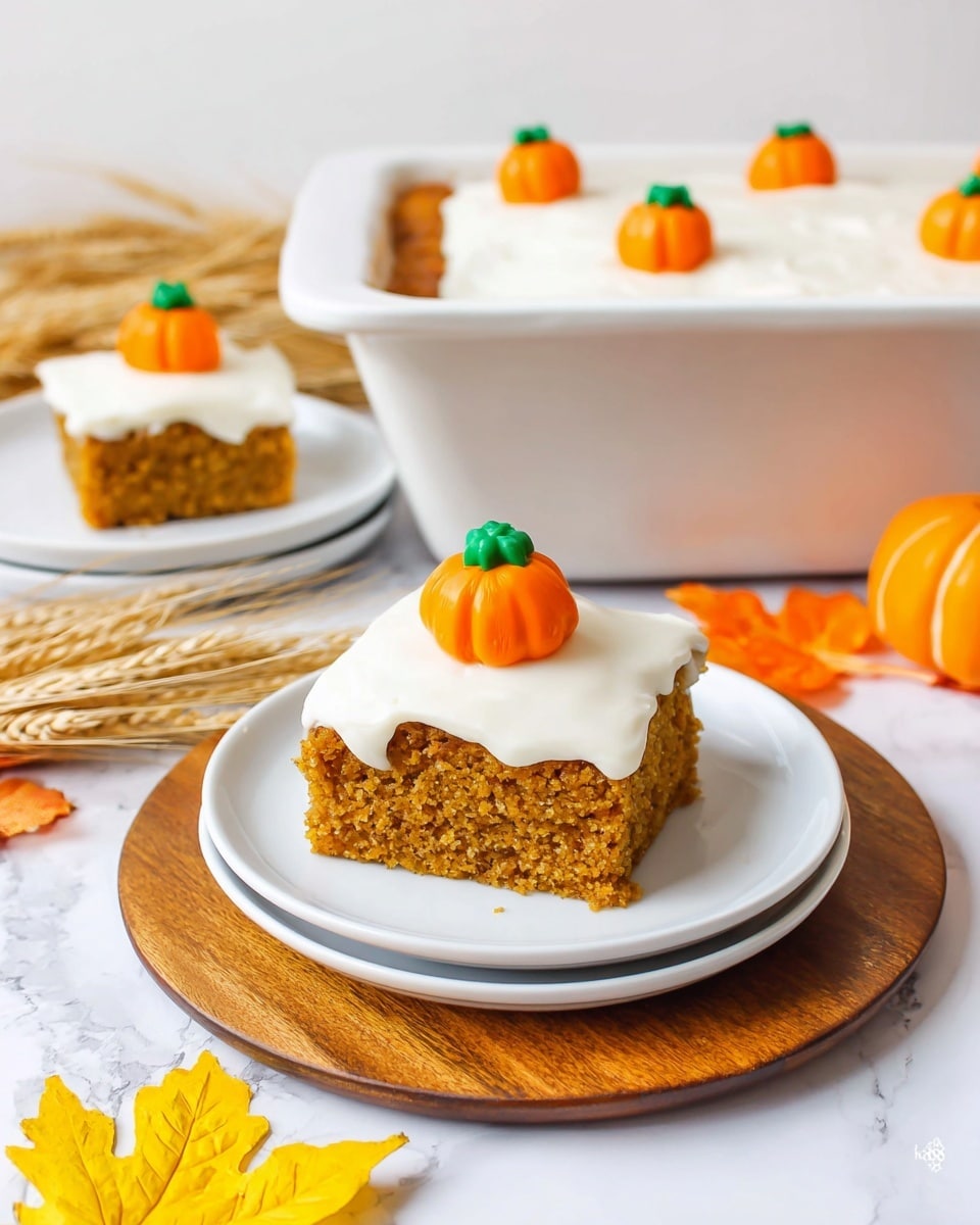 The image shows a square slice of orange-brown cake with a light and slightly crumbly texture, topped with a thick layer of smooth white frosting that slightly drips over the edges. On top of the frosting sits a small orange candy shaped like a pumpkin with a green stem. The cake slice is placed on a stack of three white plates on a round wooden board, surrounded by yellow and orange autumn leaves and wheat stalks. In the background, a white rectangular baking dish filled with the same cake is topped with more white frosting and decorated with several of the small pumpkin candies evenly spaced. Another white plate with a similar cake slice and pumpkin candy is partly visible next to the baking dish. The whole scene is set against a white marbled surface. photo taken with an iphone --ar 4:5 --v 7