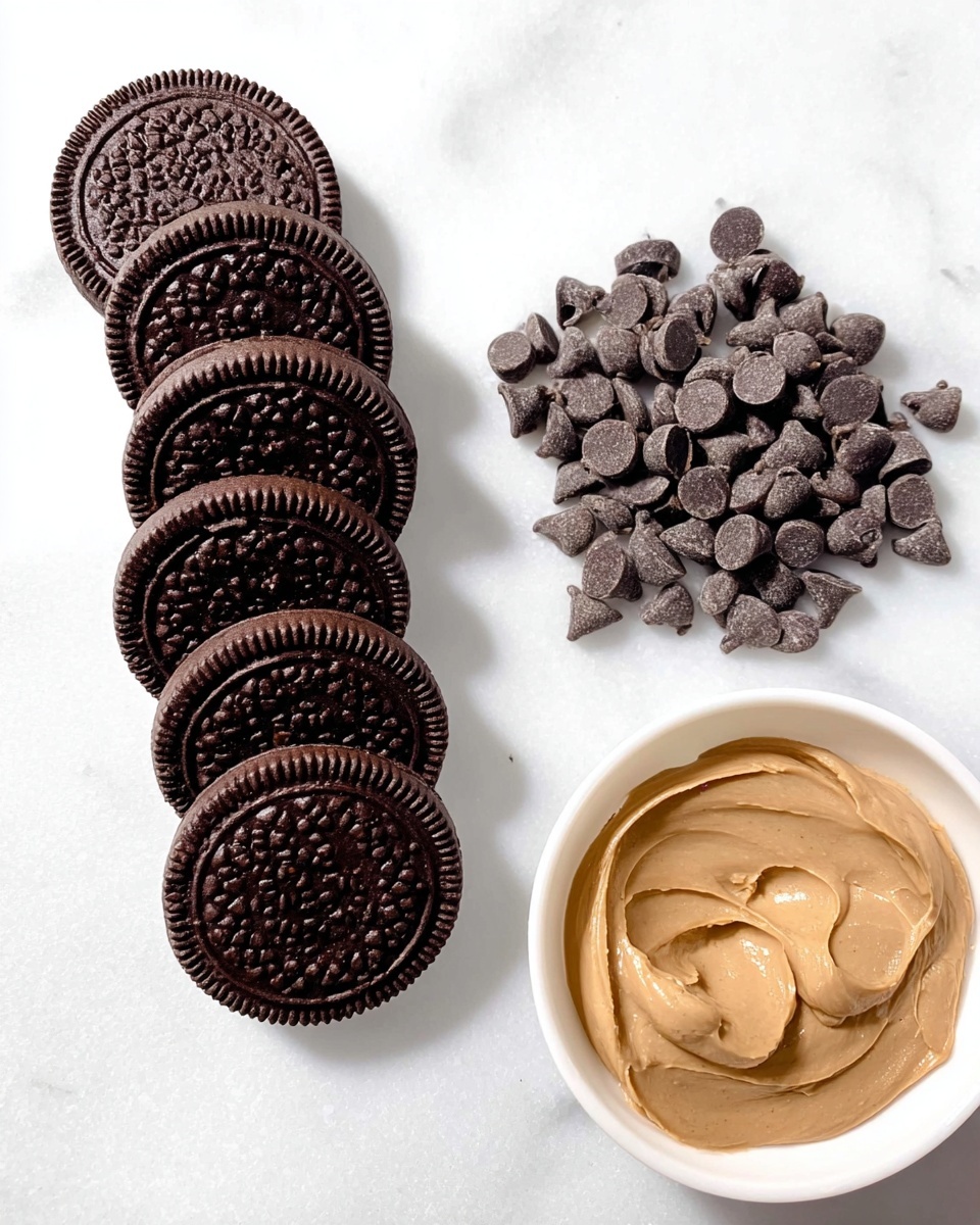 The image shows five round chocolate sandwich cookies with a textured pattern on top, arranged in a row diagonally from top left to bottom right on a smooth white marbled surface. Below and to the left of the cookies, there is a small pile of dark chocolate chips, clustered loosely together. On the bottom right side of the image, there is a white bowl containing a dollop of light brown creamy spread with a smooth and slightly shiny texture. The overall color palette contrasts dark brown elements with the light tones of the spread and white marbled background. Photo taken with an iphone --ar 4:5 --v 7