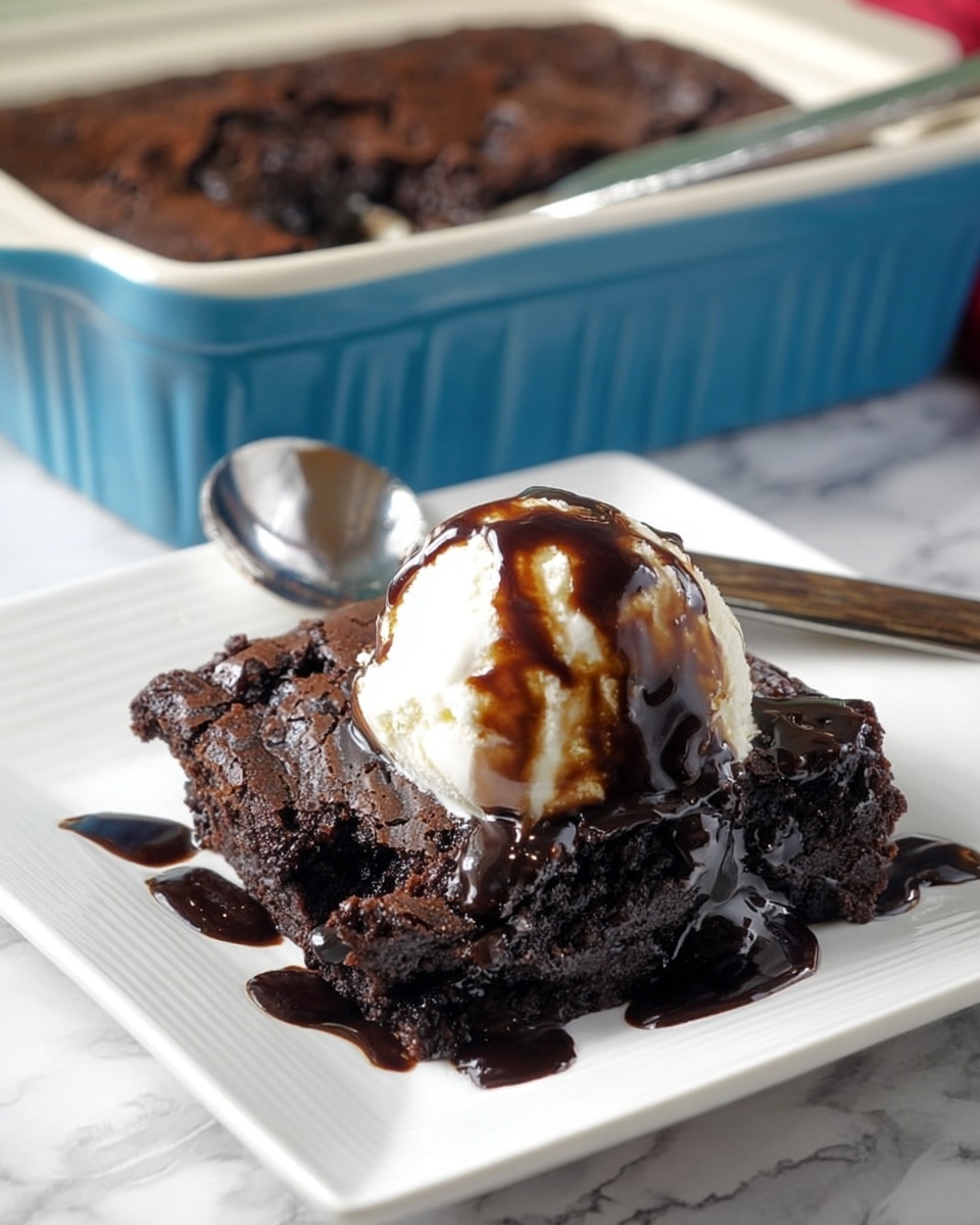 A serving of dark brown chocolate dessert with a rough, cracked texture is placed on a white square plate. On top of the dessert is a smooth white scoop of vanilla ice cream covered with glossy dark chocolate syrup drizzled loosely, some syrup also pooling at the base of the dessert. Behind the plate, a white marbled surface is visible, along with a blue baking dish containing the remaining chocolate dessert. A spoon and a knife rest on the plate near the dessert. photo taken with an iphone --ar 4:5 --v 7