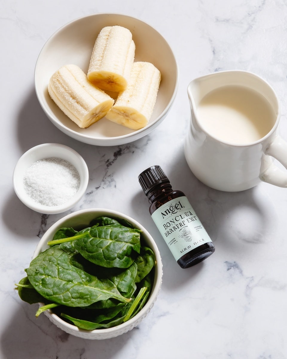 The image shows several white bowls and a white jug placed on a white marbled surface. One bowl contains four frozen banana pieces, light yellow with frost texture. Another bowl holds fresh green spinach leaves with some ice crystals. A small white round bowl contains fine white powder, while a white jug is filled with a light cream-colored liquid. A small dark glass bottle labeled 