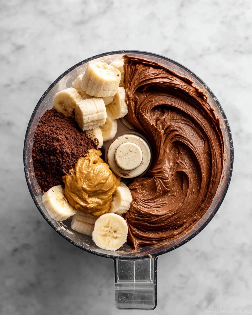 The image shows two clear food processor bowls side by side on a white marbled surface. The left bowl contains three visible layers: at the bottom, light beige banana chunks, topped with a dollop of golden peanut butter on the left side, and a pile of dark brown cocoa powder on the top right side. The right bowl shows a thick, smooth, and creamy dark chocolate mixture evenly spread around the bowl with soft swirls and the central blade slightly covered. Photo taken with an iphone --ar 4:5 --v 7
