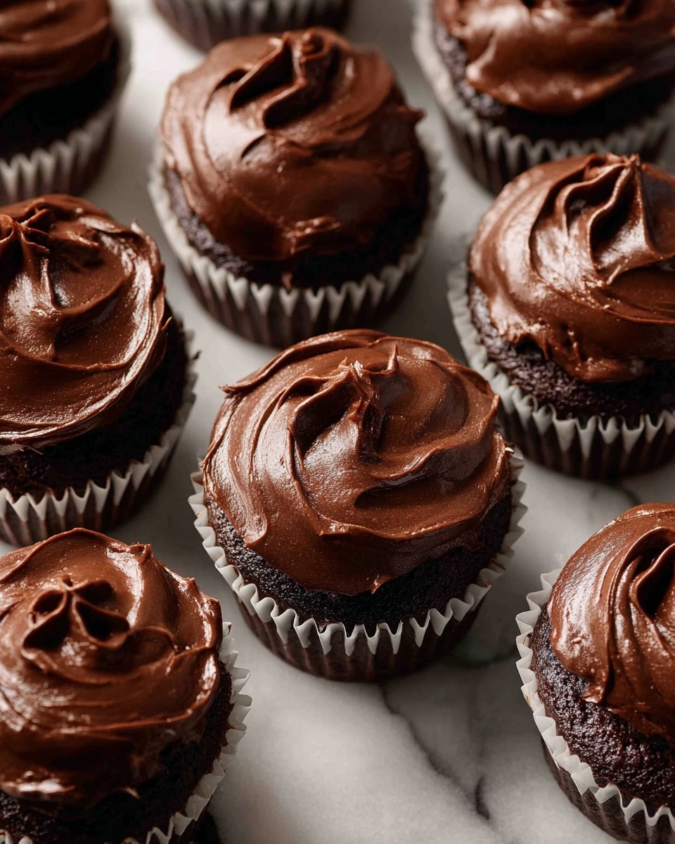 The image shows a group of chocolate cupcakes arranged closely together on a white marbled surface. Each cupcake has a rich, dark brown chocolate base with a smooth, thick layer of shiny chocolate frosting spread on top in soft swirls. The cupcakes sit in white paper liners with slight ridges around the edges. The frosting on each cupcake is uneven but glossy, with visible swirls and peaks creating a textured look. The overall color palette is deep brown from the chocolate with the white liners providing contrast. photo taken with an iphone --ar 4:5 --v 7