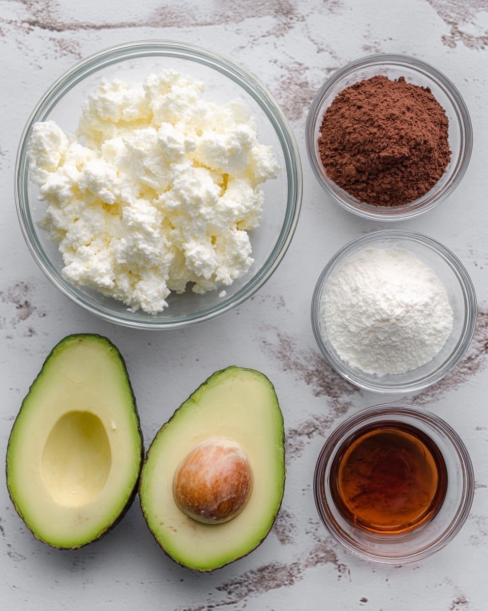 A clear glass bowl on the left filled with white cottage cheese, showing small curds and a soft texture, next to two avocado halves with green skin and light green flesh, one with a brown seed inside. To the right of the avocados, there are three small clear glass bowls arranged in a row: the first holds brown cocoa powder with a fine, slightly clumpy texture; the second contains white powdery ingredient with soft clumps; and the last has a dark amber liquid, smooth and glossy. All items are placed on a white marbled surface. Photo taken with an iphone --ar 4:5 --v 7