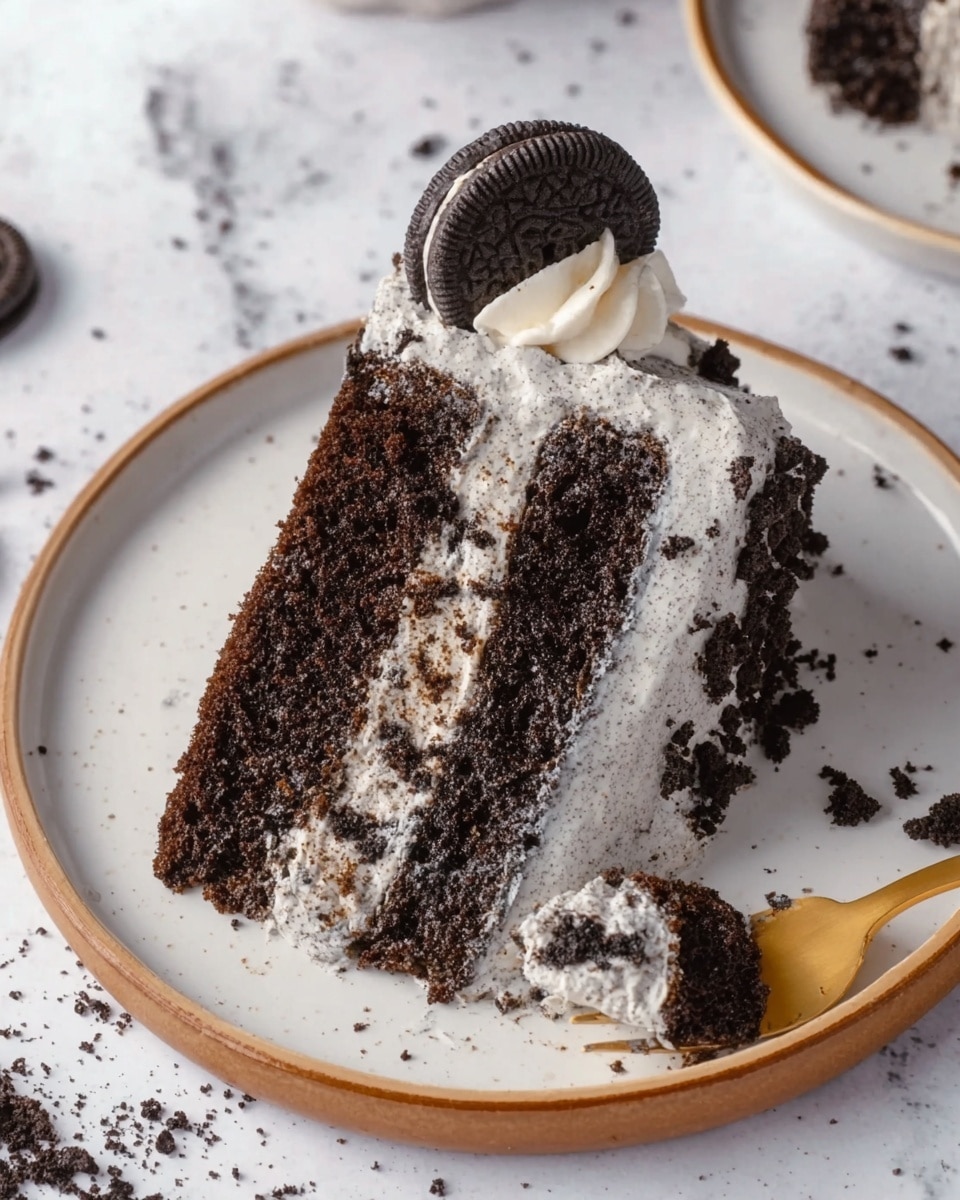 A slice of dark brown chocolate cake with two thick layers shows a creamy light gray frosting with small dark cookie bits spread all around and between the layers. The top is decorated with a swirl of white whipped cream and a whole dark chocolate sandwich cookie standing upright on it. A gold fork holds a small piece of the cake near the slice. The slice sits on a round white plate with a thin brown rim, placed on a white marbled surface with cookie crumbs scattered around. Photo taken with an iphone --ar 4:5 --v 7