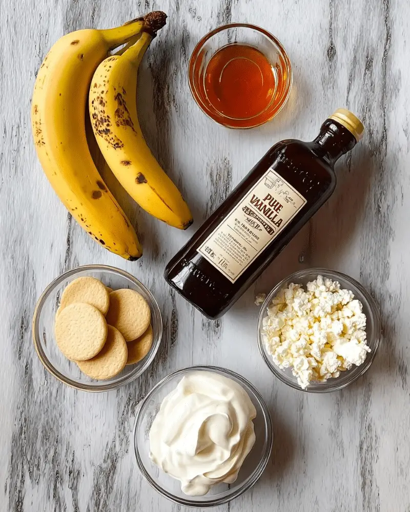 Two whole yellow bananas with brown spots lie on a white marbled surface in the top left. Above and to the right of the bananas is a small glass bowl filled with amber-colored maple syrup. Below the bananas is a dark brown glass bottle labeled