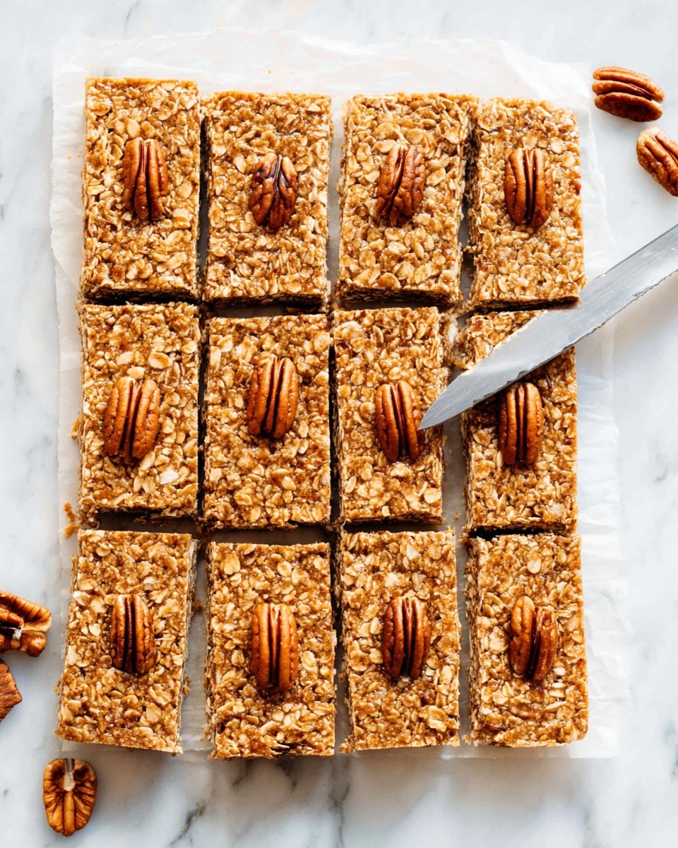 A tray of 15 oat bars arranged in three rows and five columns is shown on white parchment paper over a white marbled surface. Each rectangular bar is golden brown with textured oats mixed throughout and a single pecan half neatly placed in the center on top. A knife is slicing through one row of bars horizontally, showing neat straight edges. A few extra pecan halves are scattered near the top right corner on the white marbled surface. The lighting is bright and natural, highlighting the texture and warm tones of the oat bars photo taken with an iphone --ar 4:5 --v 7