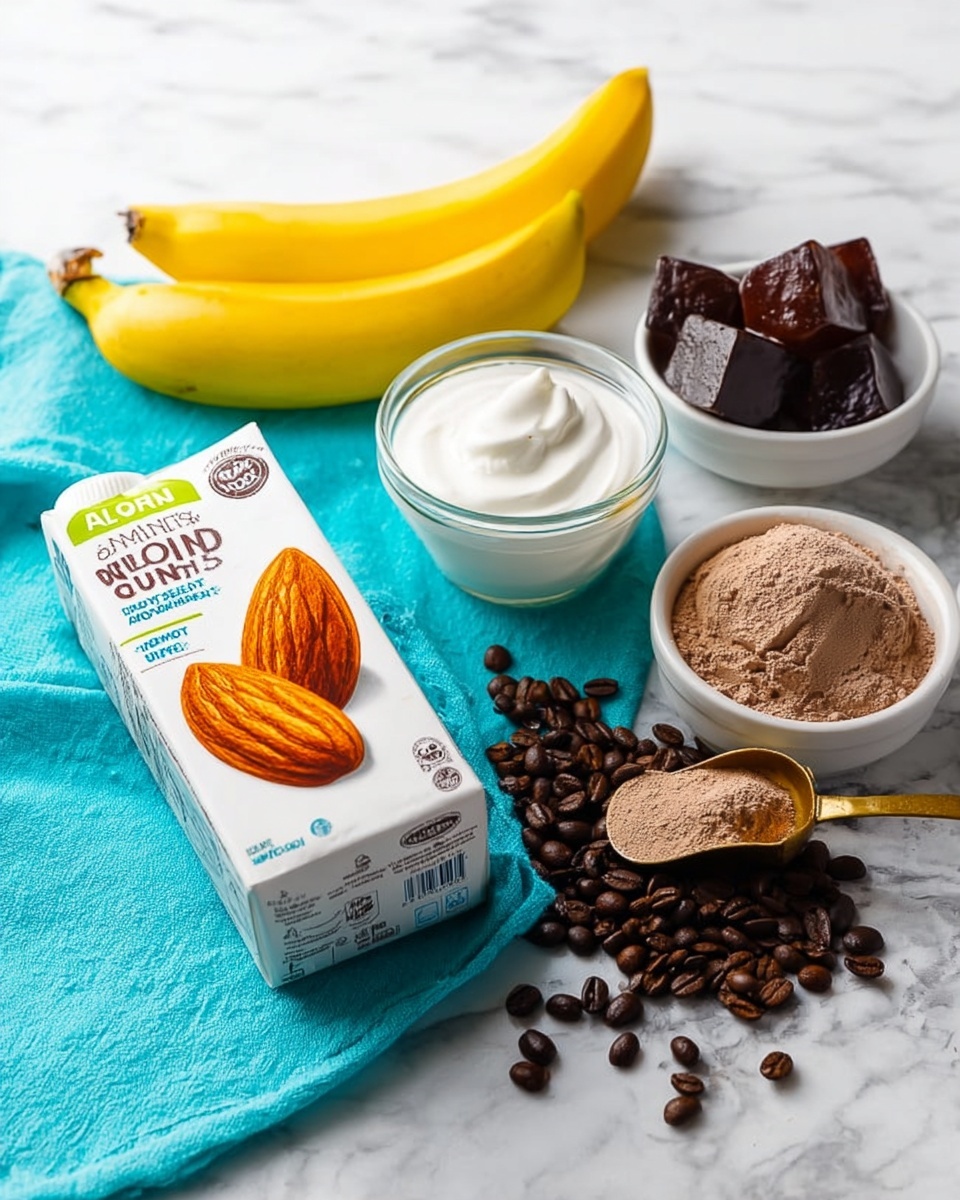 The image shows several ingredients placed on a white marbled surface: in the foreground, a white carton of unsweetened almond milk with a large almond image is tilted slightly; behind it, a small clear glass bowl filled with smooth white yogurt sits on a turquoise cloth with edges visible; next to the bowl is a bright yellow banana placed diagonally; to the right, a white bowl contains dark brown ice cubes; in front of the bowl and spread across the surface are dark brown coffee beans and a scoop filled with light brown powder, likely cocoa or coffee mix. Photo taken with an iphone --ar 4:5 --v 7