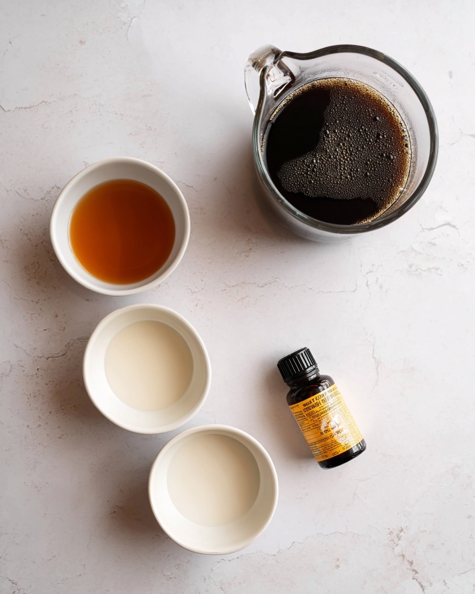 The image shows a clear glass pitcher filled with dark black coffee positioned near the top right on a white marbled surface. Below it and slightly to the left, there are three small white bowls arranged vertically. The top bowl contains a light brown liquid, the middle bowl contains a light beige liquid, and the bottom bowl holds a creamy white liquid. Next to the middle bowl on the right side, there is a small dark amber bottle labeled