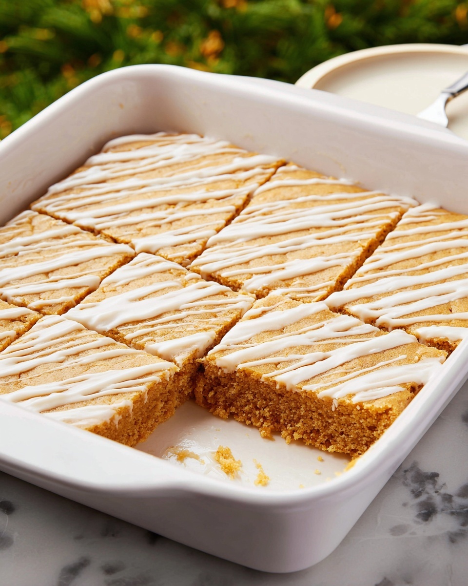 The image shows a white rectangular baking dish with a single large dessert inside, divided into smaller square pieces. The dessert has one thick layer with a golden brown color and a soft, slightly crumbly texture. On top, there is a drizzle of white icing spread evenly across the surface in thin lines. One square piece near the front left corner is missing, showing the dessert’s soft interior. The dish is placed on a white marbled surface with green blurred grass in the background and a white plate partially visible on the right side. Photo taken with an iphone --ar 4:5 --v 7