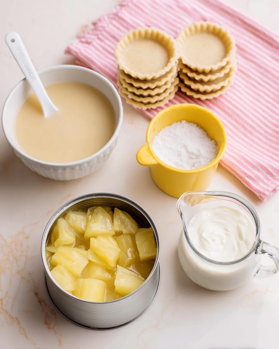 The image shows ingredients for a dessert arranged neatly on a white marbled surface. At the front center, there is an open silver can filled with yellow pineapple chunks in juice. To the left of the can, there is a white bowl with light beige creamy mixture and a white spoon sticking out of it. Behind the can and bowl, there is a stack of small white tart shells with crimped edges positioned on a pink and white striped cloth. To the right of the tart shells, there are two yellow containers; one small ramekin filled with coarse white salt and a larger measuring cup filled with white thick cream. The colors are soft and warm, creating a calm and inviting scene. Photo taken with an iphone --ar 4:5 --v 7