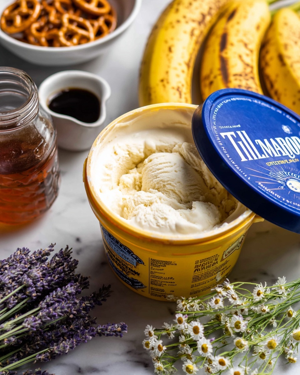 A close-up of a yellow Tillamook old-fashioned vanilla ice cream container with its blue lid being lifted, showing the creamy white ice cream inside. In the background, there are ripe bananas with brown spots, and to the left, a small white bowl filled with mini pretzels. In the foreground, there is a glass jar with amber honey, white small flowers scattered on the black surface, and a white plate holding green lavender stems with purple buds alongside a small white cup of dark vanilla extract. The entire scene is set on a white marbled surface. photo taken with an iphone --ar 4:5 --v 7