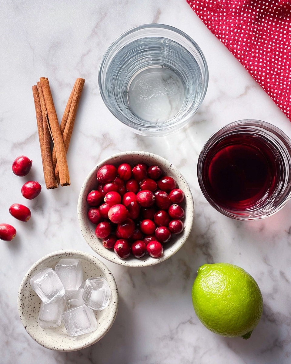 The image shows a top view of ingredients arranged on a white marbled surface, including two small white speckled bowls filled with bright red cranberries and clear ice cubes, placed side by side. To the left, two cinnamon sticks lay vertically, and three loose cranberries are scattered nearby. Above the cranberries is a clear glass filled with water, while next to it is another clear glass containing a dark red liquid. On the right side sits a whole lime with a green-yellow skin, and a red cloth with white polka dots is partially visible in the top right corner. Photo taken with an iphone --ar 4:5 --v 7