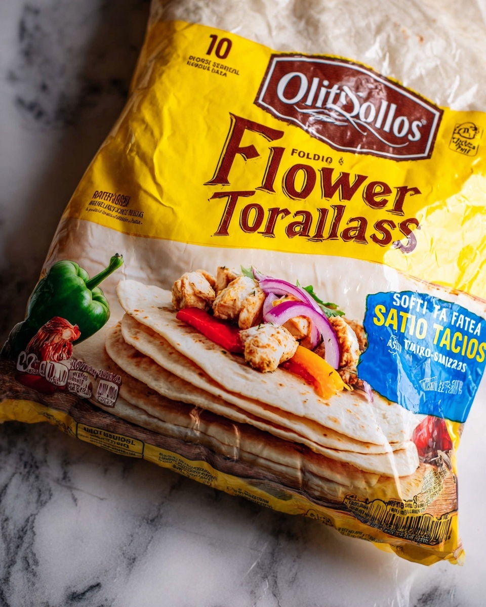 The image shows a close-up of a packaged product on a white marbled surface. The packaging is mostly bright yellow with a clear plastic part showing soft flour tortillas inside. The top of the packaging has the brand name in large brown letters on a yellow background. Below this, the text says