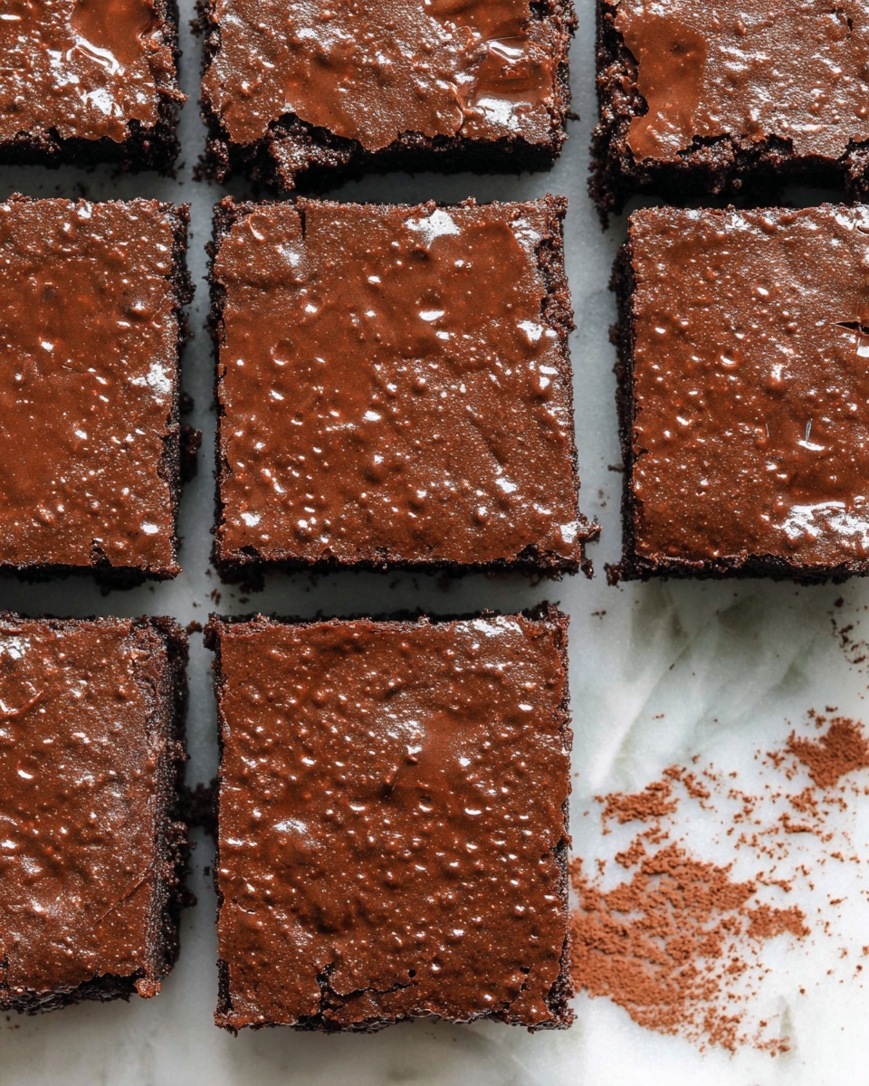 A close-up view of six square chocolate brownies arranged in two rows of three on a white marbled surface. Each brownie has a shiny, slightly cracked, dark brown top layer with tiny air bubbles, showing a dense and moist texture. The edges of the brownies are straight and clean, revealing a rich, fudgy inside. There is some loose cocoa powder scattered around the brownies on the white marbled surface, adding a rustic feel. One brownie is slightly separated from the group on the bottom right side. photo taken with an iphone --ar 4:5 --v 7