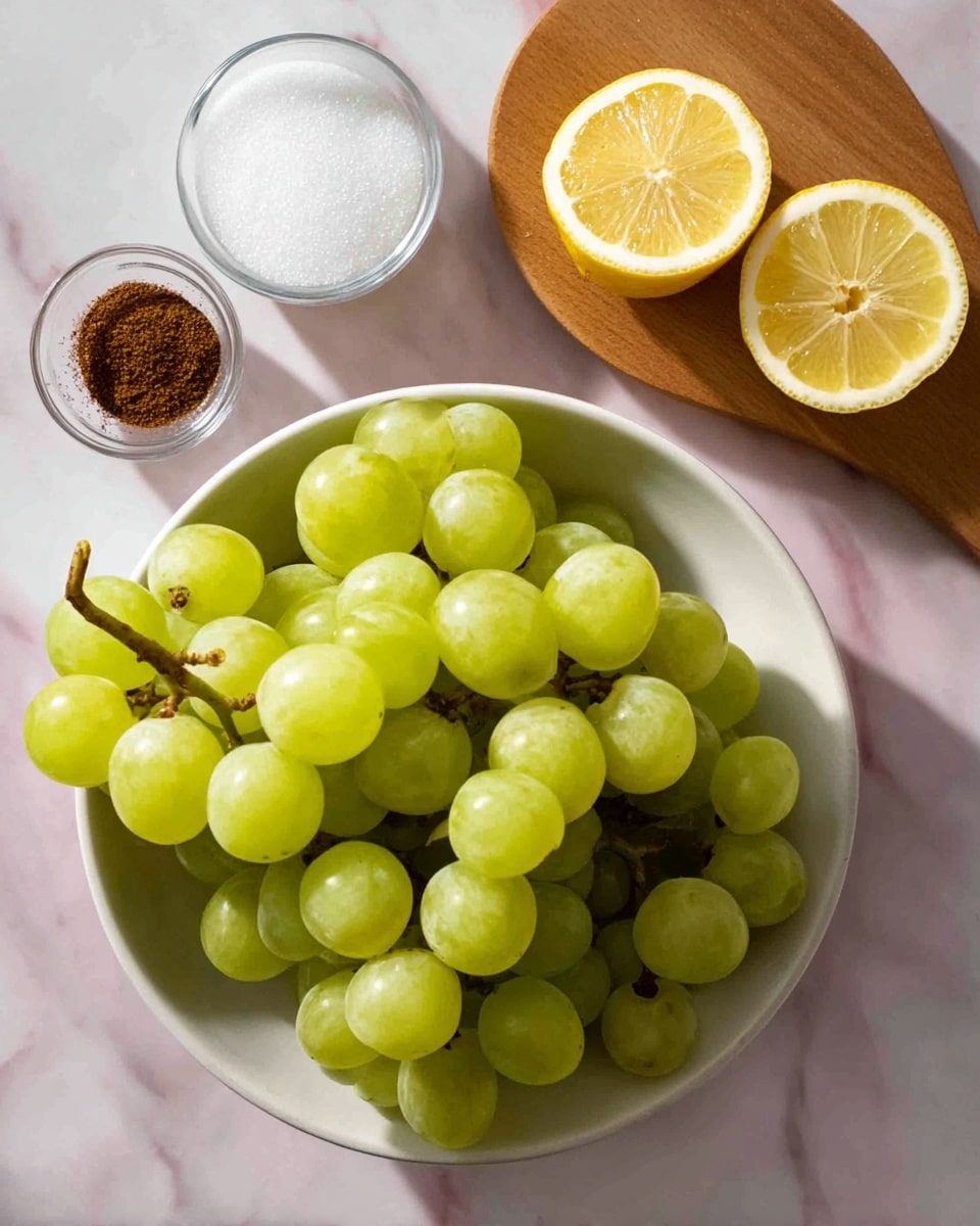 A bunch of light green grapes with smooth round skins sits in a white bowl that fills the lower part of the image; above the bowl, two lemon halves with bright yellow rinds and pale juicy insides rest on a small wooden board, next to a small glass bowl filled with white granulated sugar; to the left, a small white bowl holds a dark brown spice, all placed on a white marbled surface with soft shadows. photo taken with an iphone --ar 4:5 --v 7
