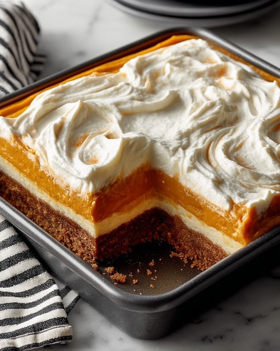 A square black baking pan holds a layered dessert with three visible layers: the bottom layer is a crumbly brown crust, the middle layer is a smooth, light orange filling, and the top layer is thick, white whipped cream spread unevenly with soft swirls. A portion is missing from one corner, showing the layers clearly. The pan is placed on a white marbled surface with a gray and white striped cloth underneath. Photo taken with an iphone --ar 4:5 --v 7