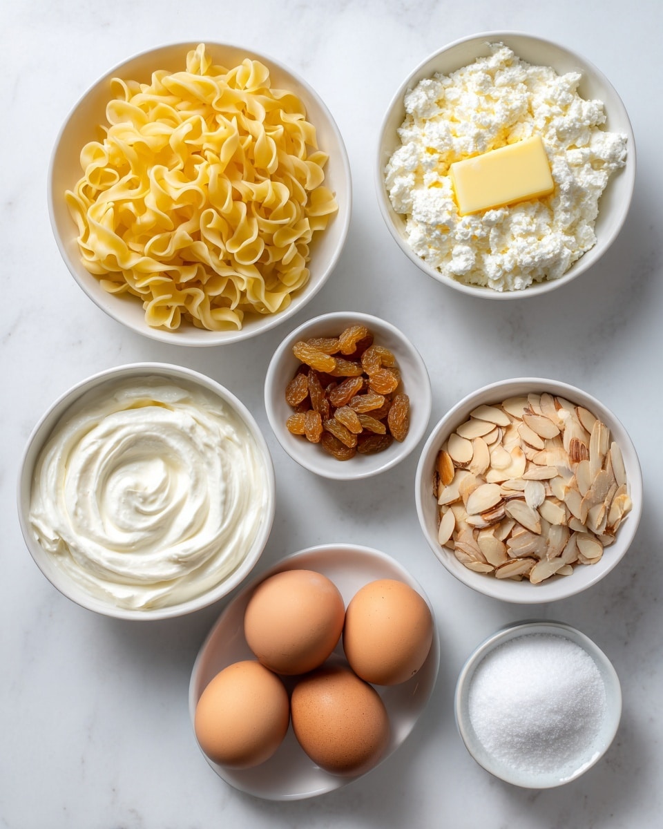 The image shows seven white bowls and a small white plate arranged on a white marbled surface. Starting from the bottom left, the largest bowl is filled with yellow uncooked pasta curls. Above that, a bowl contains melted yellow butter with a smooth surface. Next to the butter, centered near the top, a bowl is filled with white cottage cheese having a rough, lumpy texture. Below that, a bowl holds white creamy sour cream with a soft, swirled texture. To the right, there is a bowl full of light brown sliced almonds with a thin and crunchy look. Above that, a small bowl contains golden-brown raisins with a wrinkled surface. To the right of the raisins, another bowl holds white granulated sugar with a smooth surface. Finally, at the bottom right, a small white plate holds four brown eggs with a smooth, matte shell. The items are spaced evenly on the bright, clean background. Photo taken with an iphone --ar 4:5 --v 7