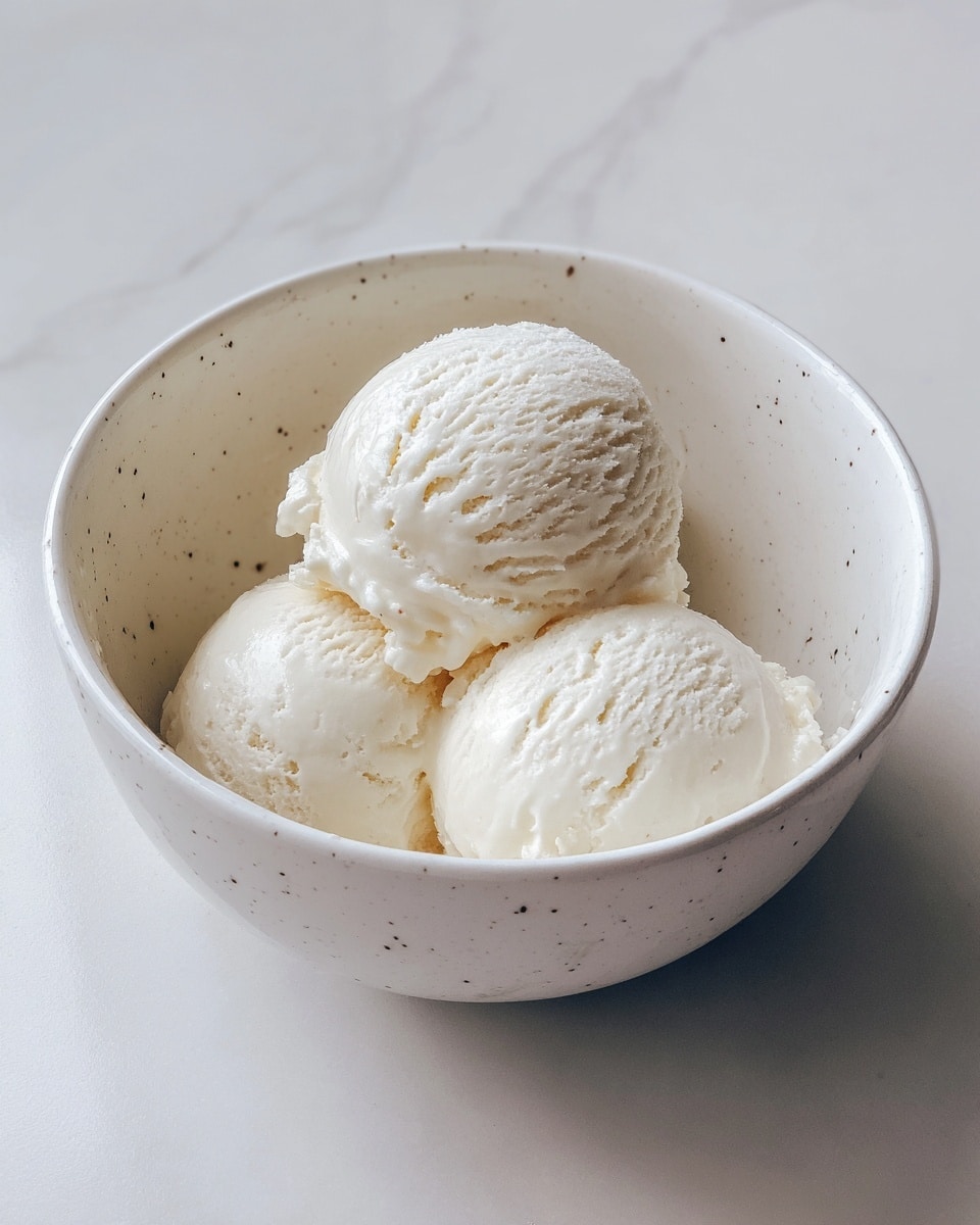 A white bowl holds three scoops of plain vanilla ice cream, each scoop round and smooth with a creamy texture, sitting close together in the bowl. The ice cream has a soft, slightly melted surface with small ice crystals visible, and the bowl is placed on a white marbled surface. photo taken with an iphone --ar 4:5 --v 7