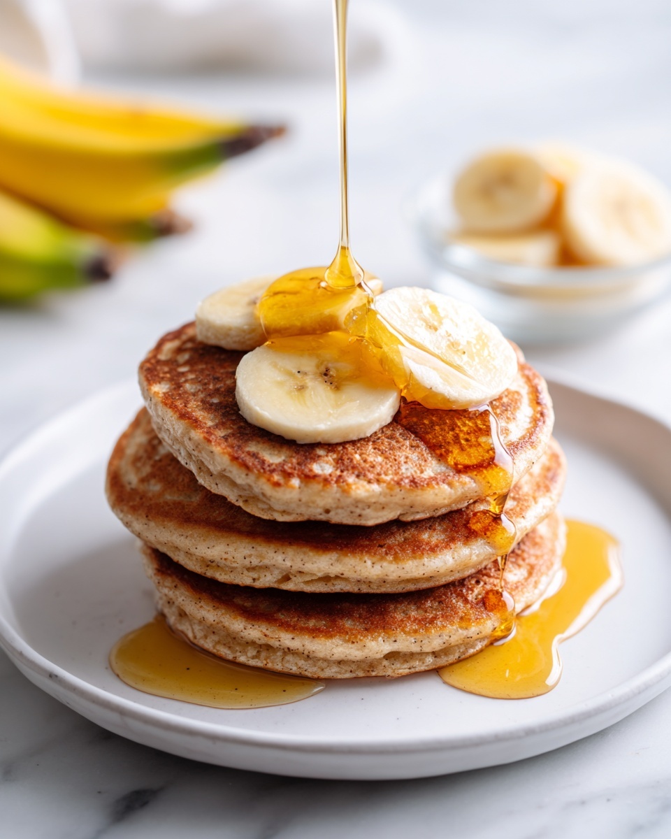 A stack of four thick, golden-brown pancakes is placed in the center of a white plate on a white marbled surface. On top of the pancakes are three round slices of banana, with more banana slices resting on the plate beside the stack. A stream of amber syrup is being poured from a glass container, flowing over the banana slices and down the side of the pancakes, creating a shiny, sticky texture. In the blurred background, there is another stack of pancakes on a white plate and a small glass bowl with additional banana slices. photo taken with an iphone --ar 4:5 --v 7