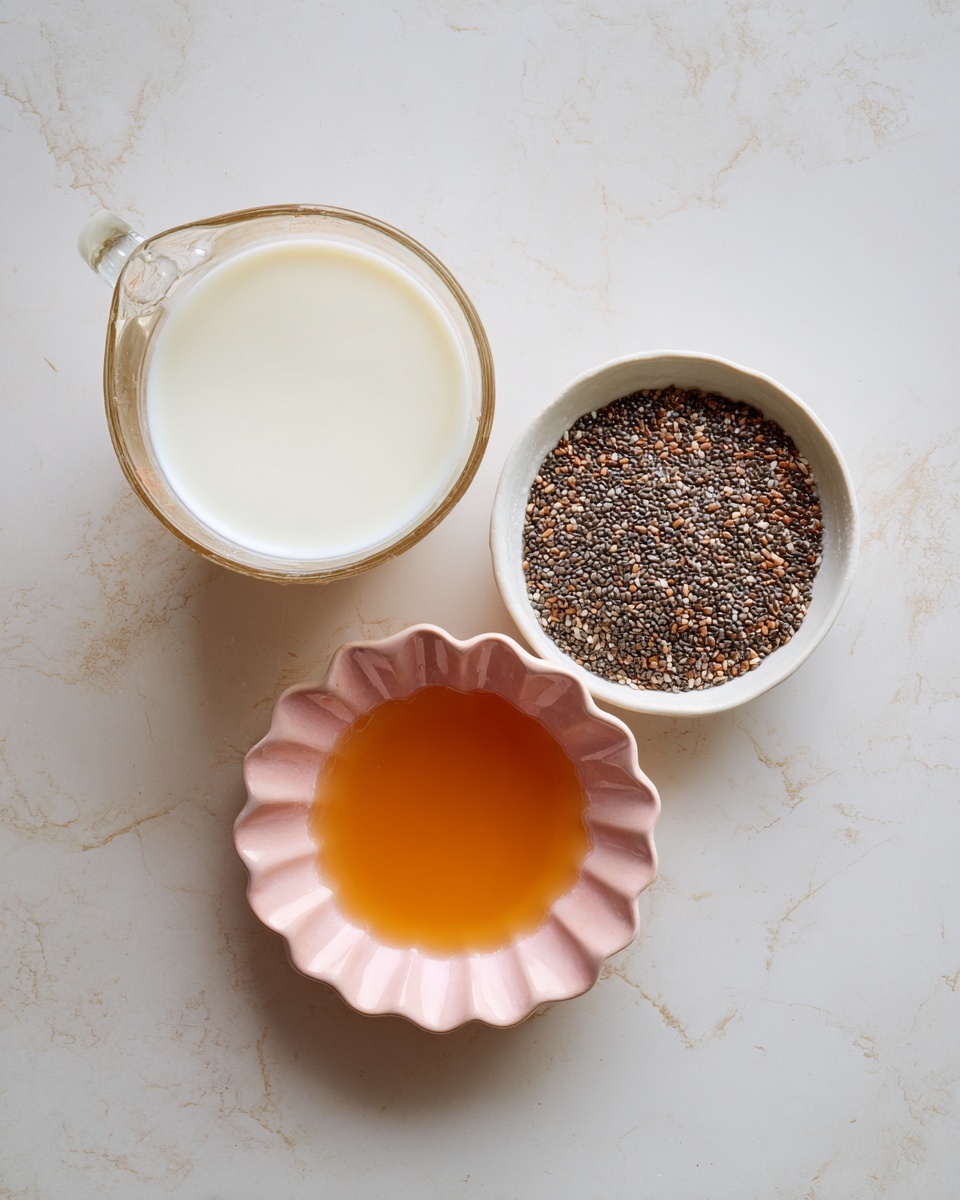 A clear glass measuring cup filled with smooth, white milk sits at the top center on a white marbled surface. Below it, there are three small white bowls arranged in a slight arc; the right bowl is full of small, dark chia seeds with mixed shades of brown and black, the left bowl holds an amber-colored liquid, and the bottom bowl contains a similar amber liquid but in a pink, scalloped dish. The overall scene is simple and clean, highlighting the different textures and colors of the ingredients. photo taken with an iphone --ar 4:5 --v 7