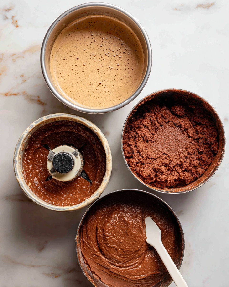 The image shows four metal mixing bowls and a food processor on a white marbled surface. The top left bowl has a light brown smooth batter with tiny bubbles, evenly spread inside. The top right bowl holds a thicker, darker brown dough with a rough texture, spread around the bowl's sides. The bottom left shows a food processor blade surrounded by a chunky, dark reddish-brown mixture with a slightly shiny texture. The bottom right bowl contains the thick brown dough spread inside, with a dark chunky mixture placed in the center and a white spatula resting on the bowl's edge. photo taken with an iphone --ar 4:5 --v 7