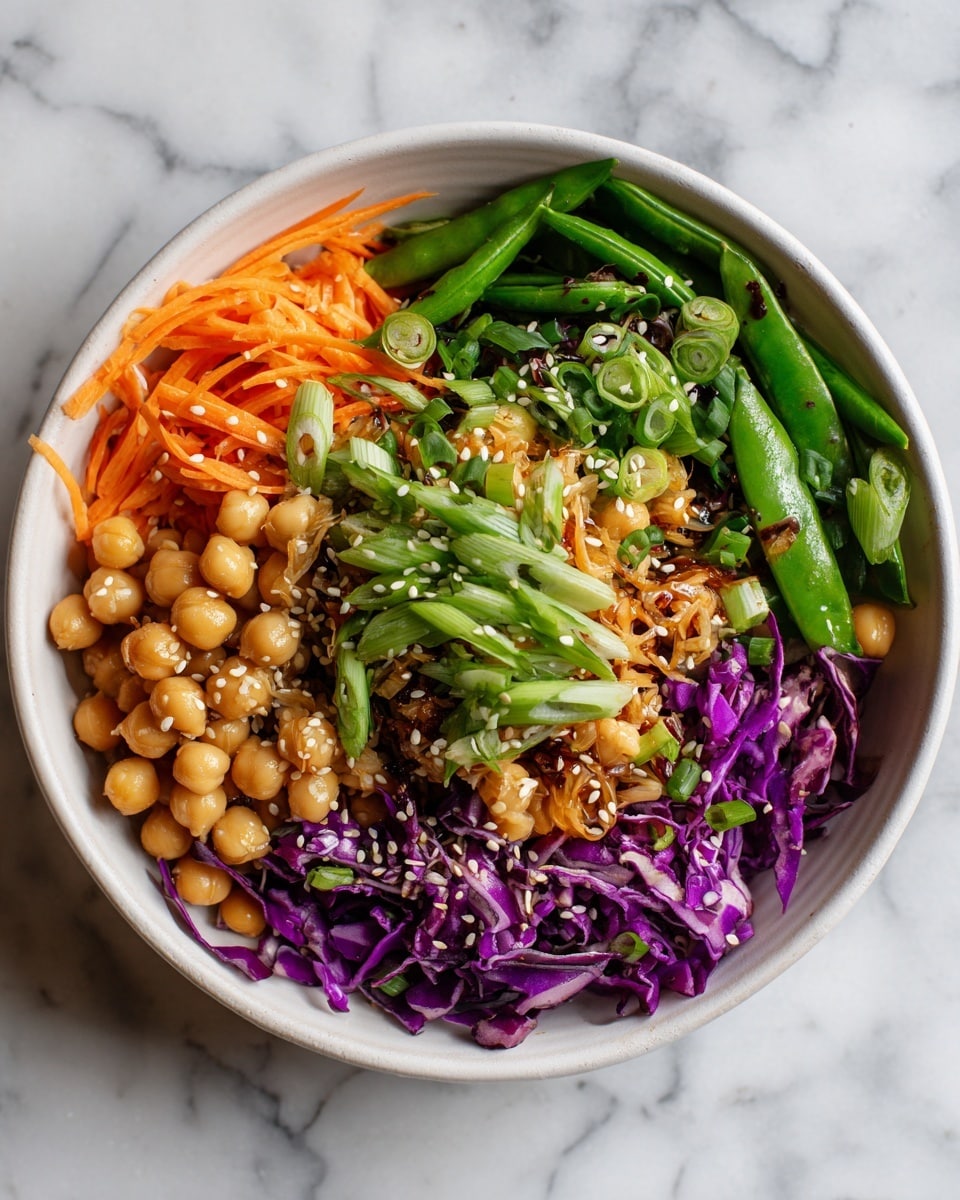 The dish is shown in a white bowl, filled with multiple layers of ingredients. The bottom layer is made up of shredded purple cabbage and orange carrots. On top of that, there is a thick layer of light brown chickpeas spread across one side of the bowl. Covering the other side are bright green snap peas sliced in halves and quarters. A generous pile of thinly sliced green onions is placed over the snap peas and partially over the chickpeas. The dish is sprinkled with small sesame seeds and has a fresh and colorful look. The setting features a white marbled surface. Photo taken with an iphone --ar 4:5 --v 7