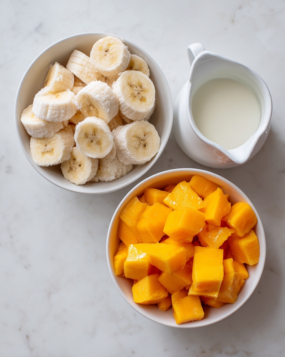 The image shows three white bowls placed on a white marbled surface. The top left bowl contains peeled, frozen banana pieces that are light cream in color with a rough, frosty texture. The bottom bowl is filled with bright orange frozen mango chunks that have a slightly icy texture. To the right, there is a small white pitcher filled with a smooth, white liquid, likely coconut milk or cream. The arrangement is simple and neat, with a bright and fresh look. photo taken with an iphone --ar 4:5 --v 7