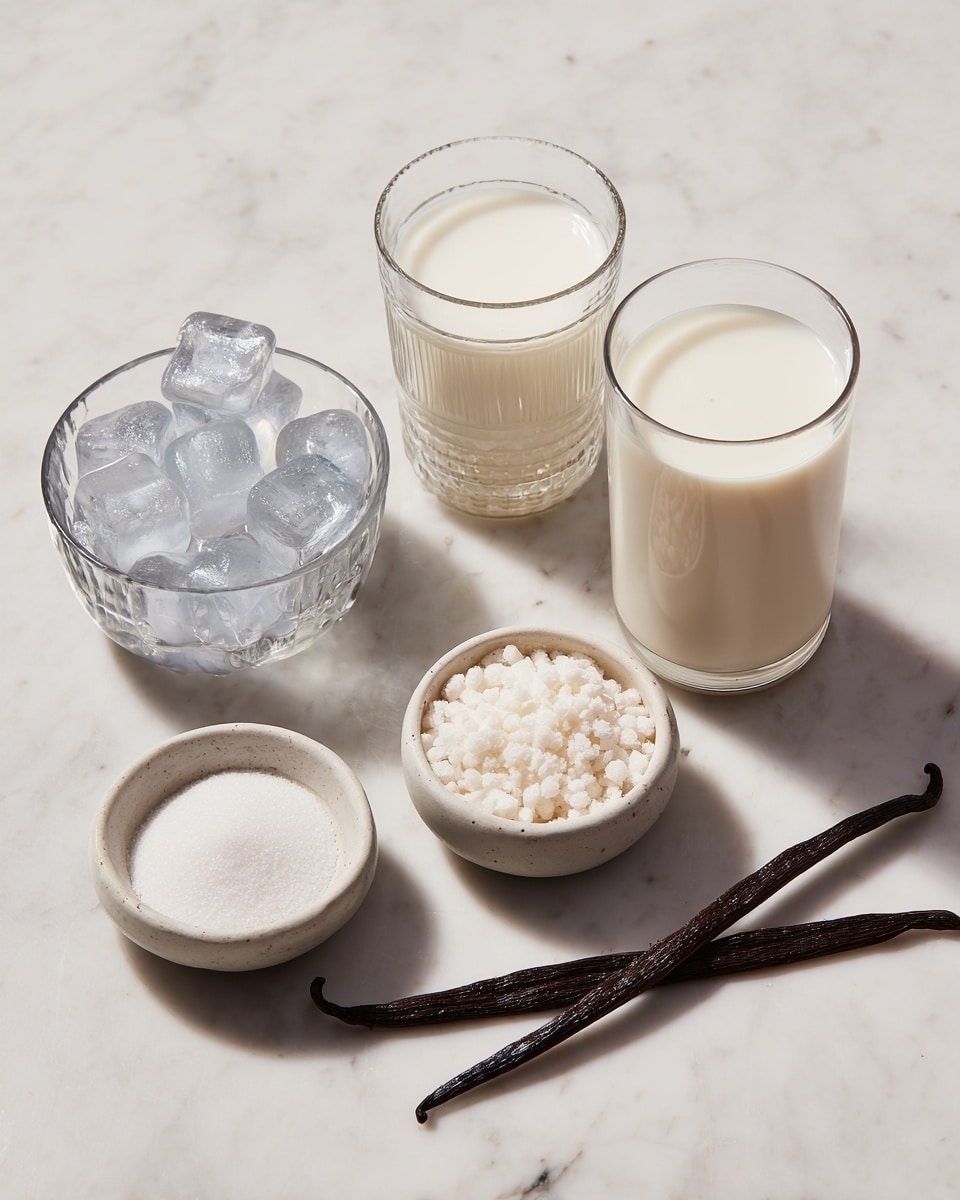 The image shows six items placed on a white marbled surface. There are two clear glass cups filled with a creamy white liquid, one taller and rounder on the right, the other shorter and with a ring pattern on the left. In front of these cups, there is a small clear glass bowl filled with round ice cubes. Next to it, there are two small white ceramic bowls, one containing white granulated sugar and the other a white powdery substance. Lastly, there is a long dark brown vanilla bean pod lying horizontally beside the bowls. Photo taken with an iphone --ar 4:5 --v 7