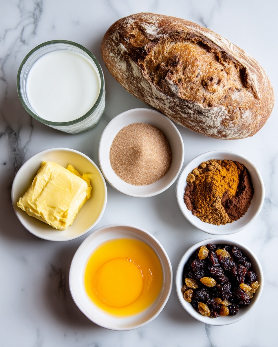 The image shows six small white bowls and a glass cup arranged on a white marbled surface with a loaf of bread placed above them. The glass cup on the left holds white milk. Below it, a white bowl contains yellow melted butter with a smooth surface. Next to the milk is a bowl with bright orange beaten egg. To the right, a bowl with light brown soft brown sugar that looks fine and powdery is placed. Above it, a bowl holds a mix of cinnamon, nutmeg, and mixed spice with a dark brown powdery texture. Lastly, a bowl filled with dark mixed fruit pieces, including raisins and other dried fruits, sits at the bottom right. The loaf of bread above all bowls has a light golden crust with deep cracks. The photo was taken with an iphone --ar 4:5 --v 7