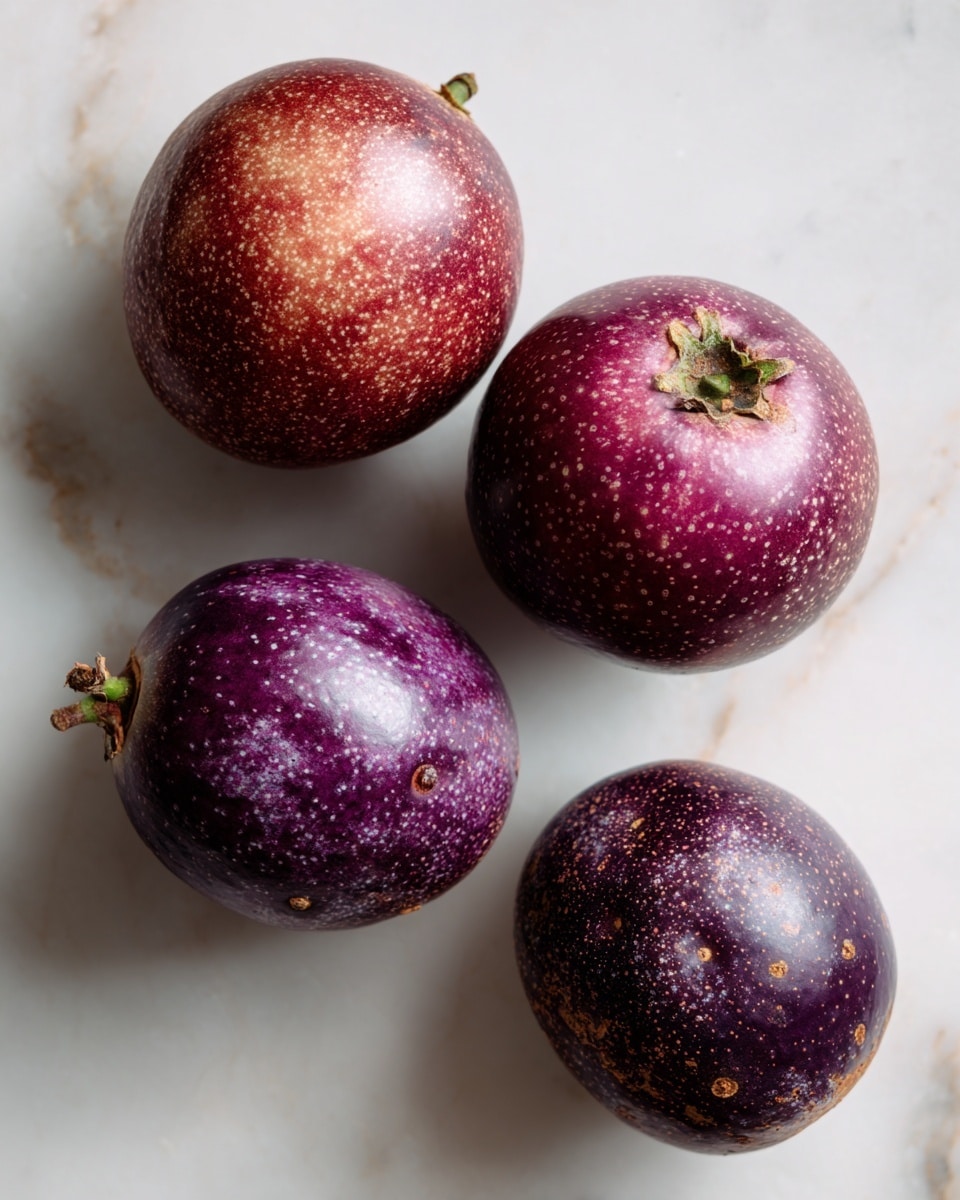 The image shows four whole purple passion fruits with rough, speckled skins in various shades of deep purple and reddish-brown. Two fruits at the top have smoother, rounder skins with small brown spots, while the two at the bottom are more wrinkled and uneven in texture. Each fruit has a small greenish stem attached at the top. They are placed on a white marbled textured surface, with soft lighting making the skins slightly shiny. photo taken with an iphone --ar 4:5 --v 7