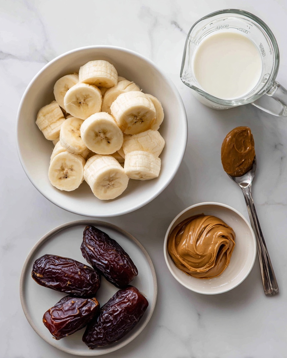 The image shows frozen banana slices piled in a white bowl on the left side. Below the bowl are four dark brown dates with wrinkled textures. To the right of the dates, there is a small white bowl with golden brown syrup inside. Above this bowl, there is another small white plate holding a silver spoon with a dollop of thick peanut butter on it. At the top center, there is a clear glass measuring cup filled with white milk. All these items rest on a white marbled surface. photo taken with an iphone --ar 4:5 --v 7